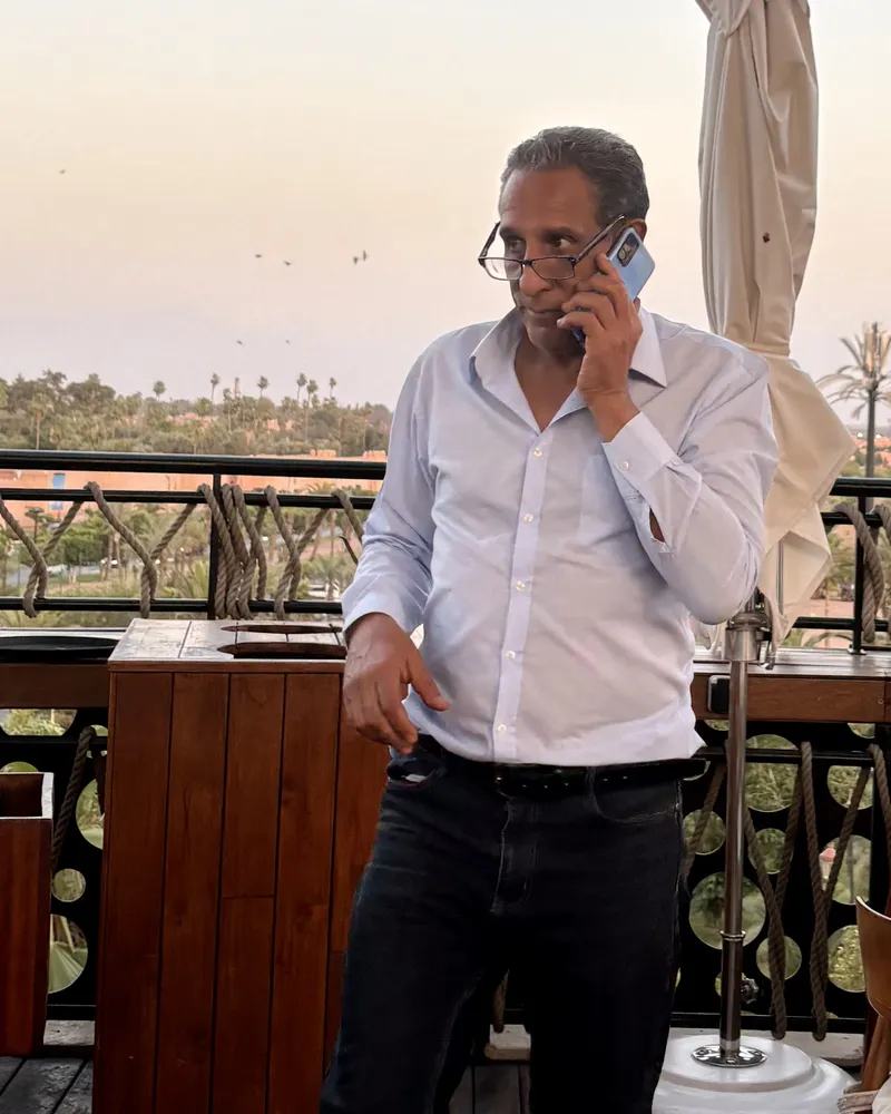 Sakine Meliani on a phone call on a rooftop terrace above the palms, 2026